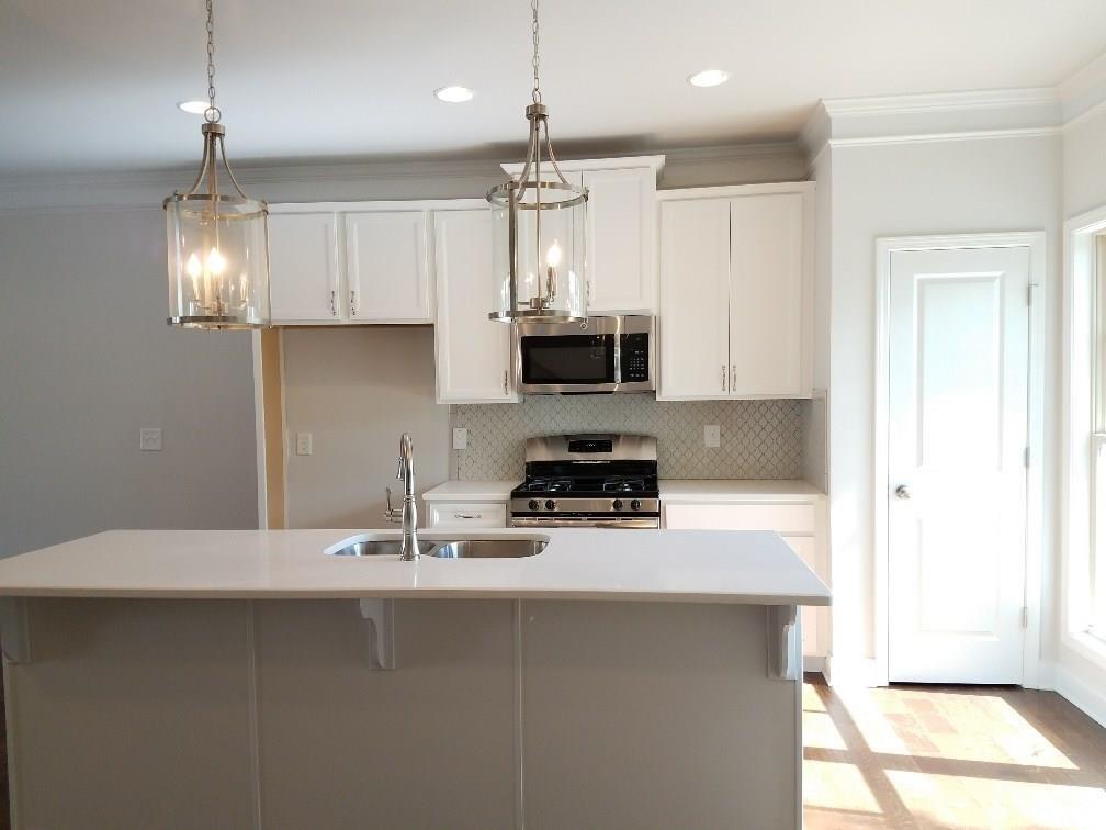 1450 Baygreen Road Suwanee, GA 30024 - Photo 5 of 7 a kitchen with kitchen island granite countertop a sink a counter space appliances and cabinets