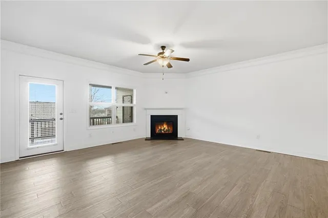 a view of a livingroom with a ceiling fan wooden floor and windows