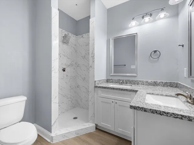 a bathroom with a granite countertop sink a toilet and shower