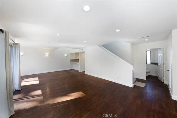 a view of a big room with wooden floor and windows