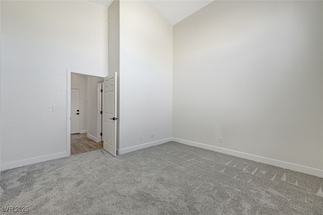 1995 Thunder Ridge Circle Henderson, NV 89012 - Photo 20 of 47 Empty room with high vaulted ceiling, carpet, and baseboards