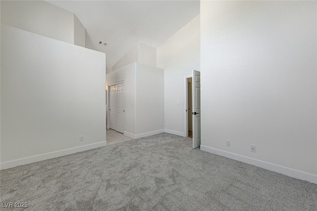 1995 Thunder Ridge Circle Henderson, NV 89012 - Photo 21 of 47 Unfurnished room with high vaulted ceiling, baseboards, light colored carpet, and visible vents