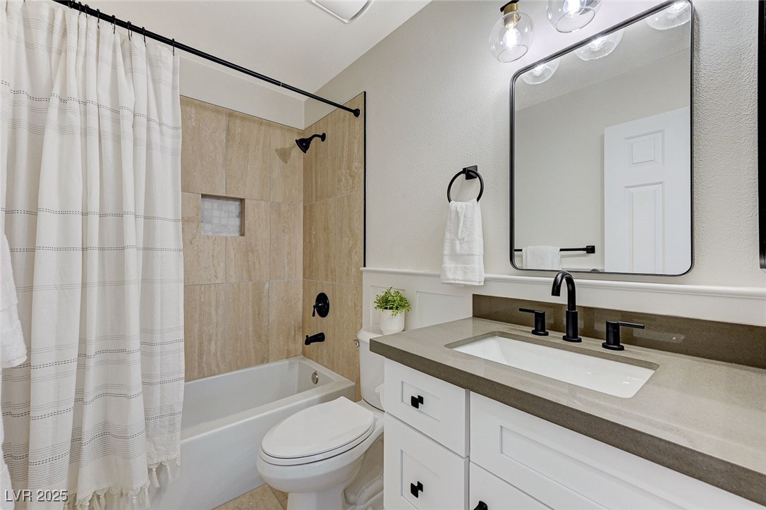 1995 Thunder Ridge Circle Henderson, NV 89012 - Photo 32 of 47 Bathroom with toilet, shower / bath combo with shower curtain, vanity, and wainscoting