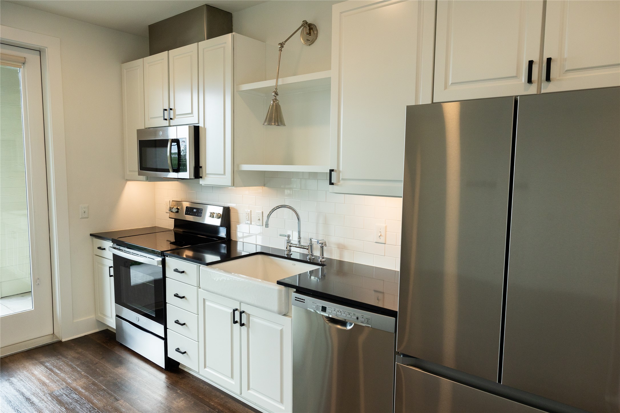 4704 Sunset Trail, Unit 1203 Austin, TX 78745 - Photo 8 of 26 Kitchen featuring stainless steel appliances, white cabinets, open shelves, decorative backsplash, and dark wood-style floors