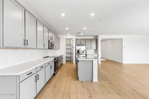a kitchen with stainless steel appliances kitchen island wooden floors and white cabinets