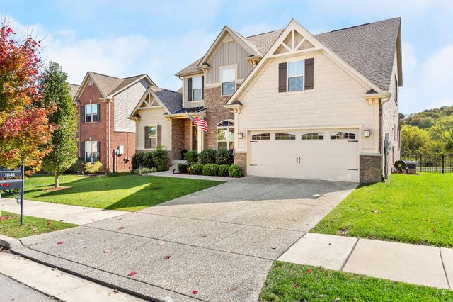 a view of a white house next to a yard and a large tree