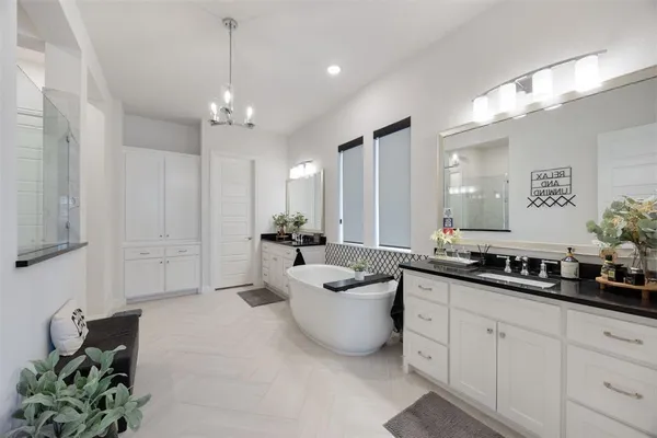 a bathroom with a double vanity sink a mirror a bathtub and shower