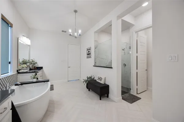 a spacious bathroom with a double vanity sink a mirror a bathtub and a shower