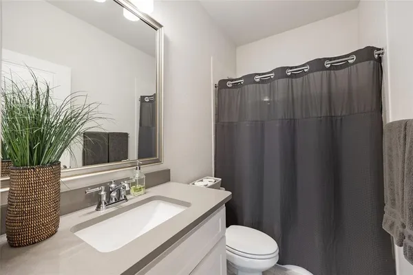 a bathroom with a sink a toilet a mirror and shower curtain