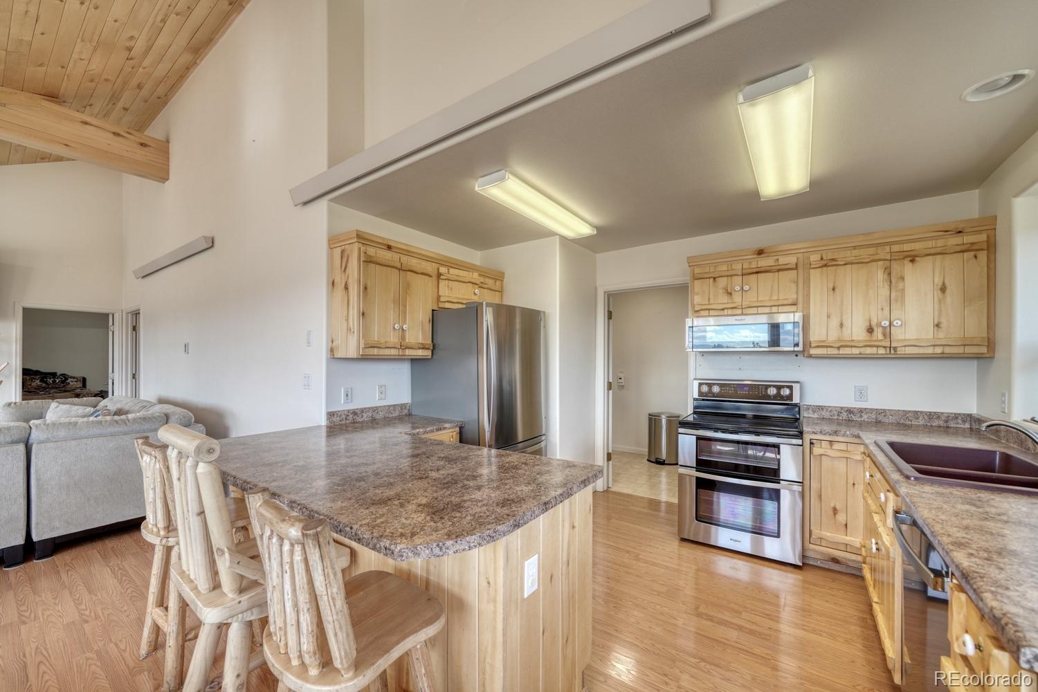 31015 West Ridge Road Buena Vista, CO 81211 - Photo 7 of 48 a kitchen with stainless steel appliances granite countertop a stove top oven a sink dishwasher a dining table and chairs with wooden floor