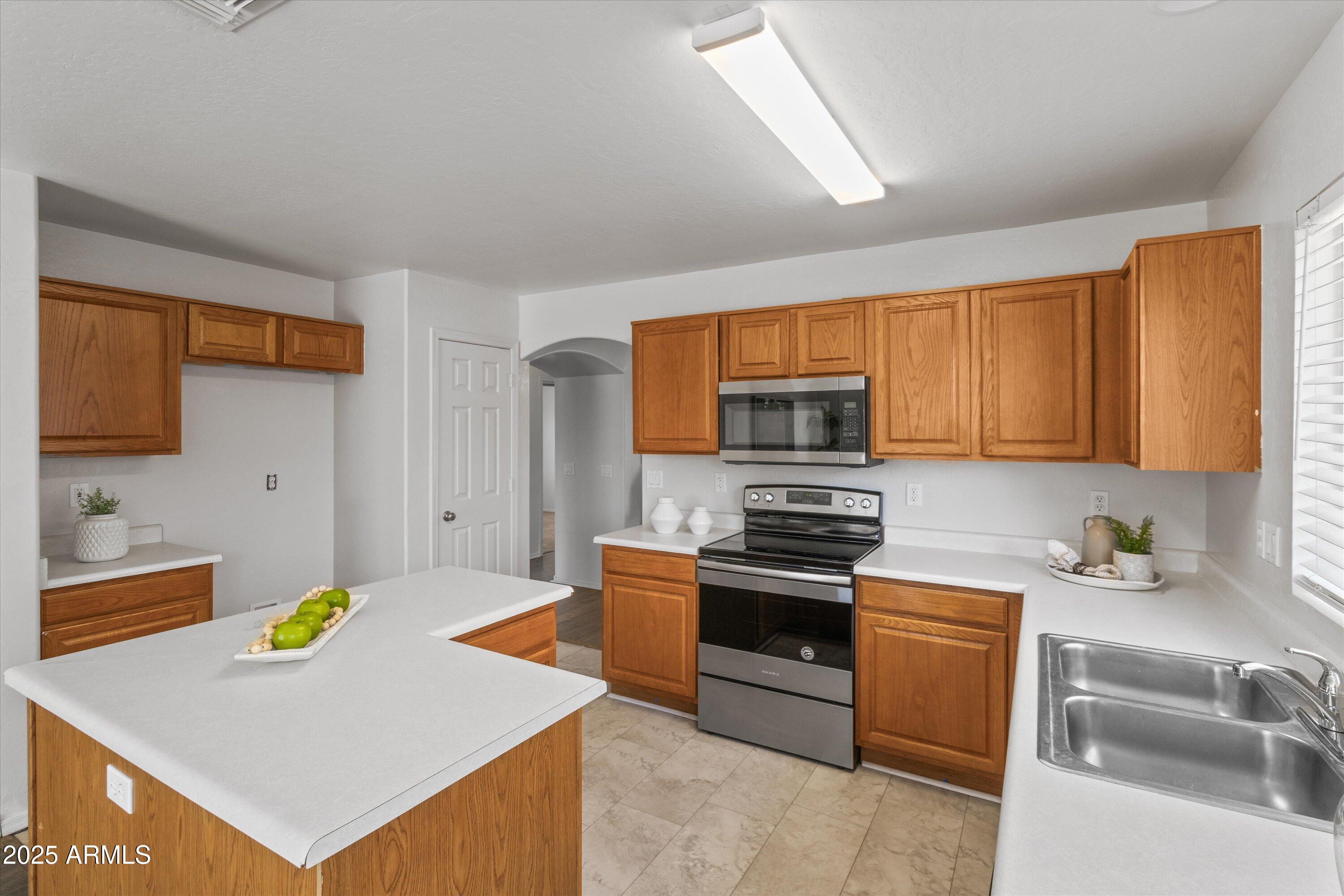 11921 West Bloomfield Road El Mirage, AZ 85335 - Photo 8 of 24 a kitchen with stainless steel appliances a stove a sink cabinets and a refrigerator