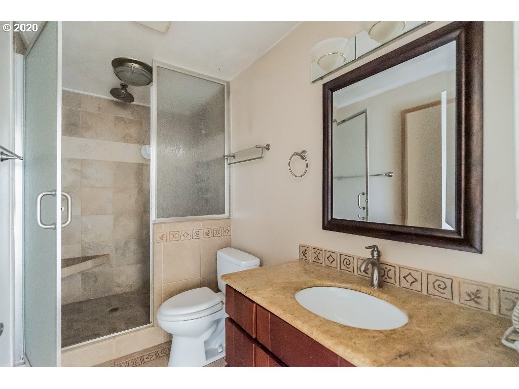 5620 Southwest Riverside Lane Portland, OR 97239 - Photo 24 of 25 a bathroom with a granite countertop sink toilet a mirror and shower