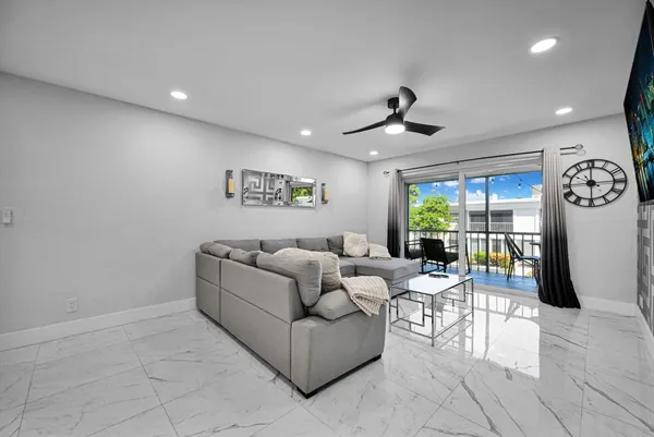 a view of swimming pool that has lawn chairs potted plants and palm trees