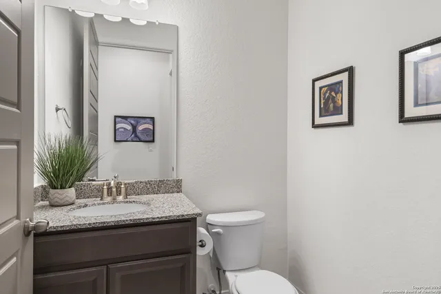 a bathroom with a granite countertop toilet sink and mirror
