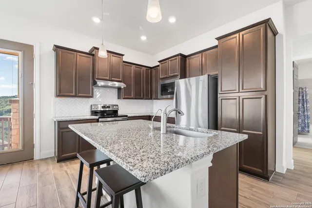 a kitchen with stainless steel appliances granite countertop a sink stove and refrigerator