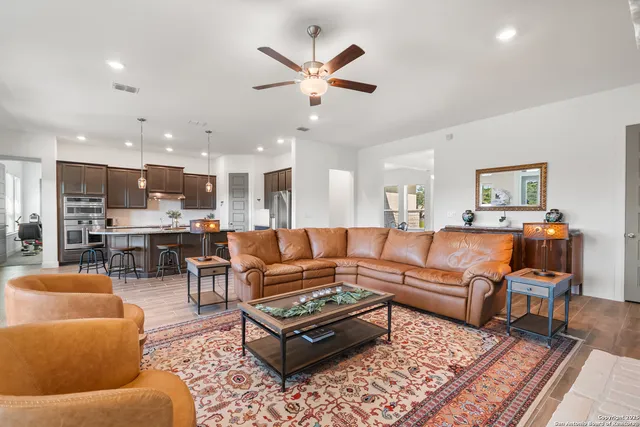 a living room with furniture kitchen view and a chandelier