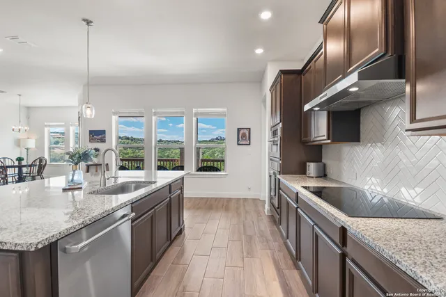a kitchen with stainless steel appliances granite countertop a sink a stove and a wooden floors