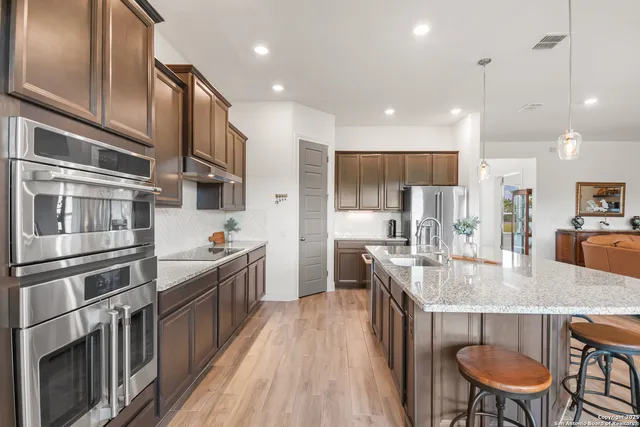a kitchen with stainless steel appliances granite countertop a kitchen island wooden cabinets and refrigerator
