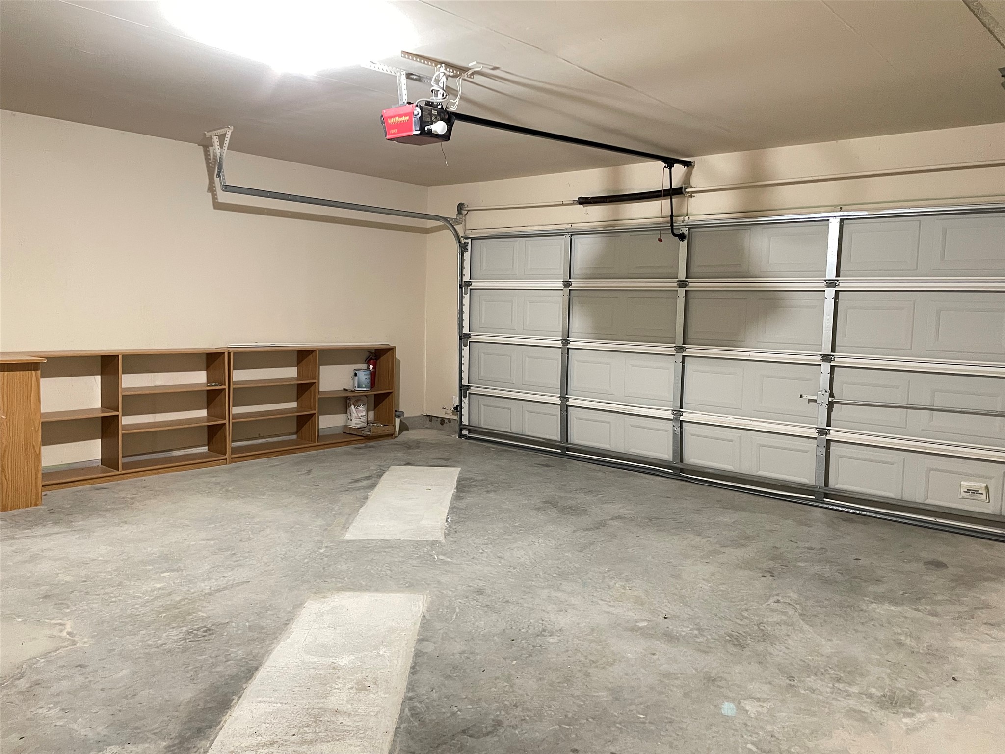 11713 Dunblane Way Austin, TX 78754 - Photo 20 of 22 Spacious garage featuring a concrete floor, two sectional overhead doors, and built-in wood-finish shelving