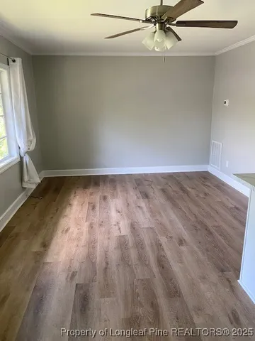an empty room with wooden floor fan and windows