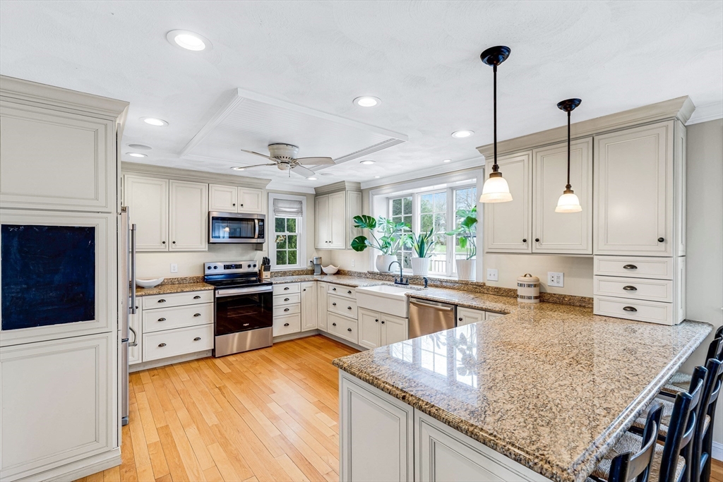 54 Old Merrill Street Amesbury, MA 01913 - Photo 11 of 34 a kitchen with stainless steel appliances granite countertop a stove top oven a sink a center island and cabinets