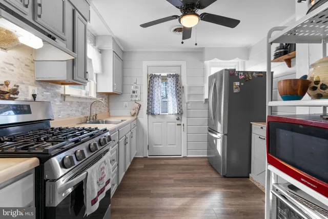 a kitchen with stainless steel appliances a refrigerator and a hard wood floor