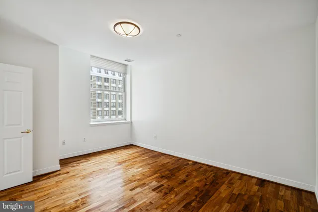 an empty room with wooden floor and window