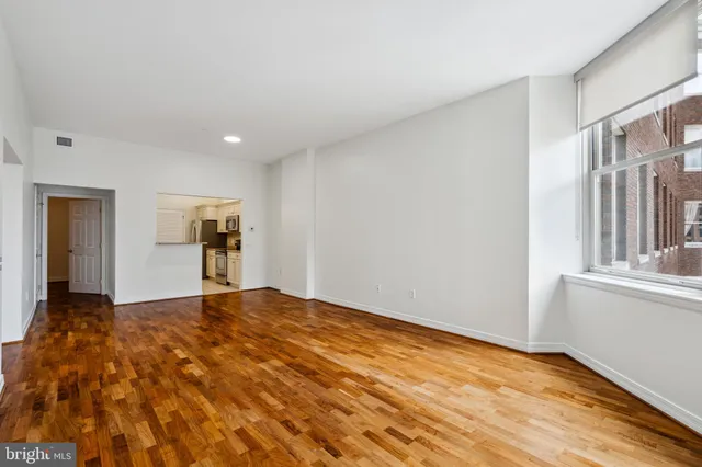 a view of an empty room with window and wooden floor