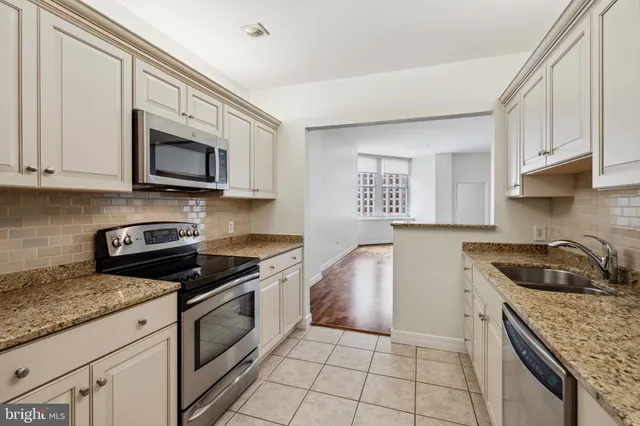a kitchen with granite countertop a sink a stove and cabinets