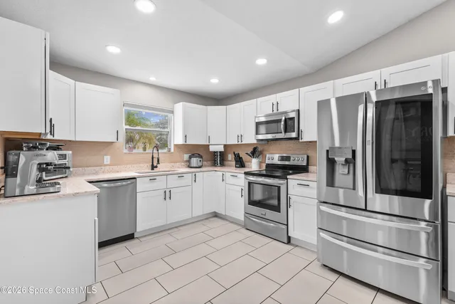 a kitchen with stainless steel appliances granite countertop a refrigerator a stove a sink and a microwave