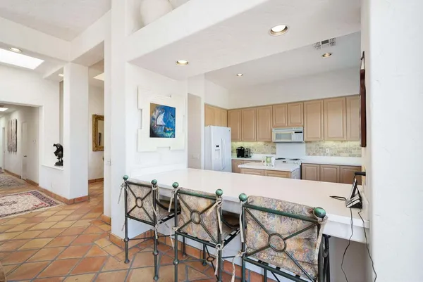 a kitchen with stainless steel appliances kitchen island granite countertop a dining table chairs and a refrigerator