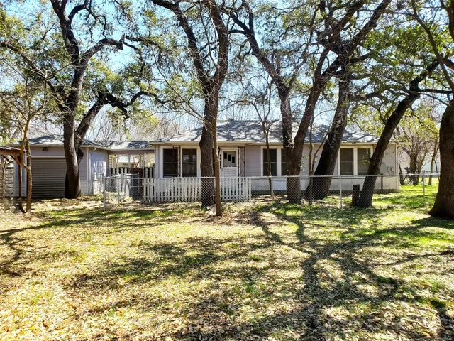 a backyard of a house with large trees and plants