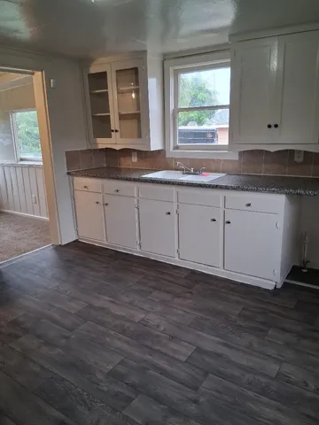a kitchen with granite countertop wooden cabinets a sink and a window