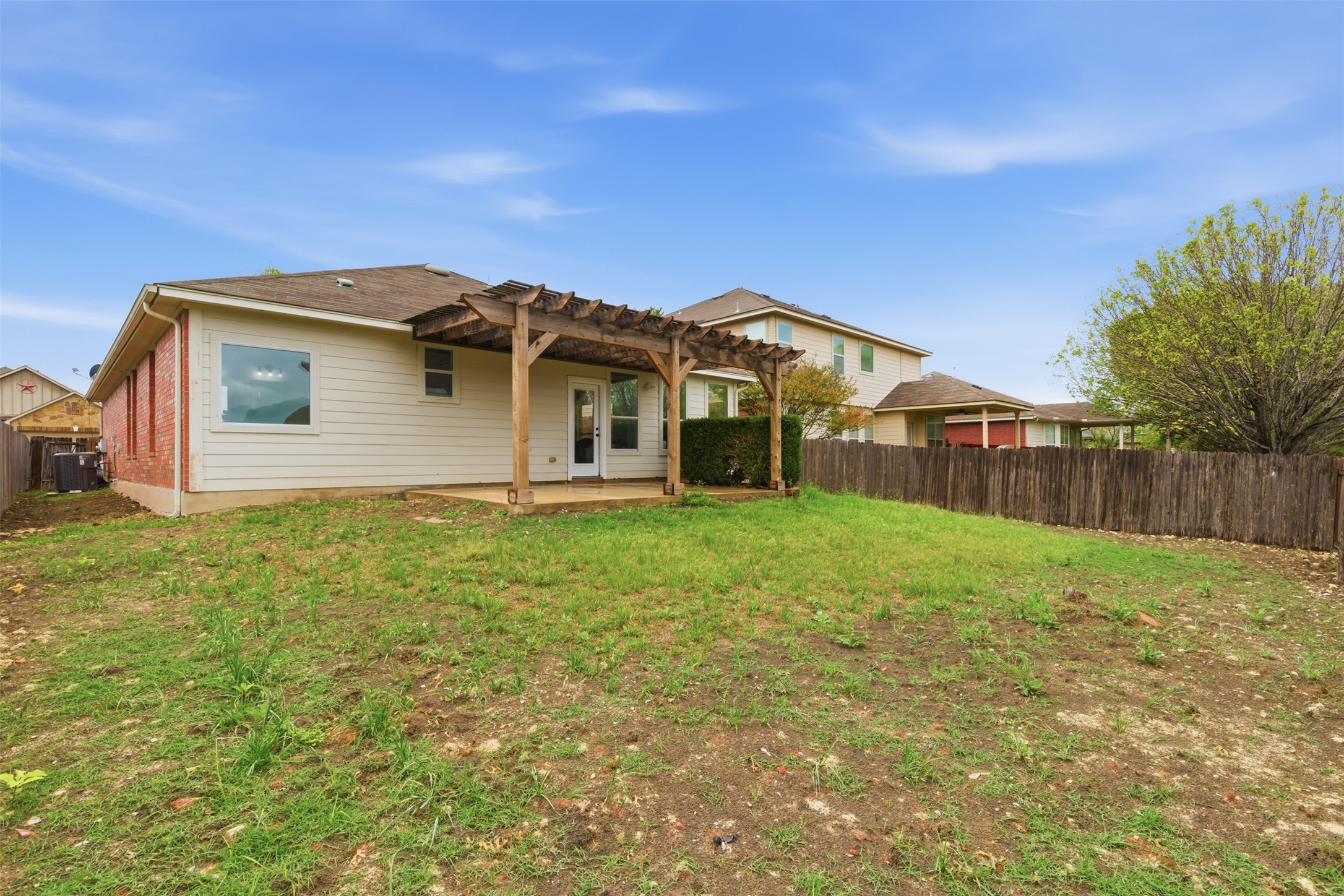 461 Hot Spring Valley Buda, TX 78610 - Photo 22 of 25 The property features a spacious rear yard with a wooden privacy fence and a pergola-covered patio area