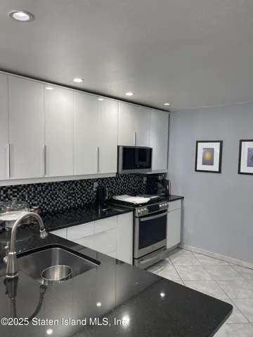 a kitchen with stainless steel appliances granite countertop a sink a stove and a microwave