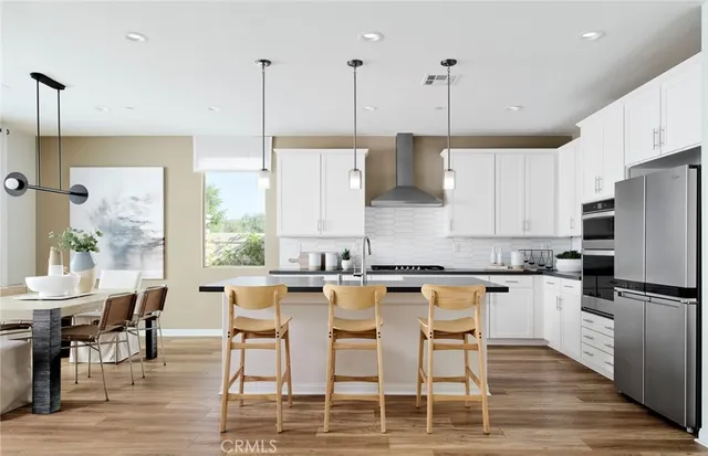 a kitchen with stainless steel appliances granite countertop a table chairs stove and wooden floor