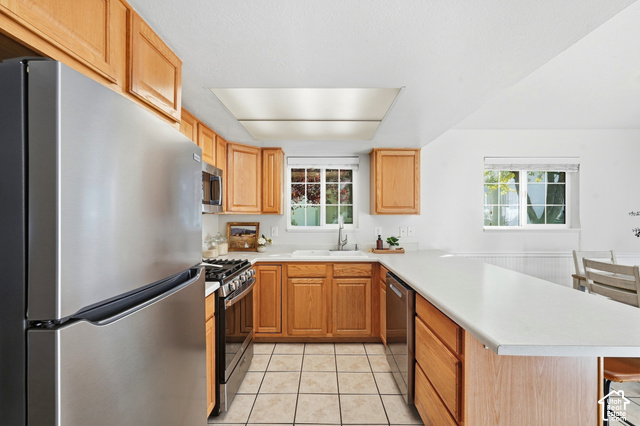 108 Penhurst Place Logan, UT 84341 - Photo 15 of 44 U-shaped kitchen with wood cabinetry, stainless steel appliances, white countertops, and tiled flooring