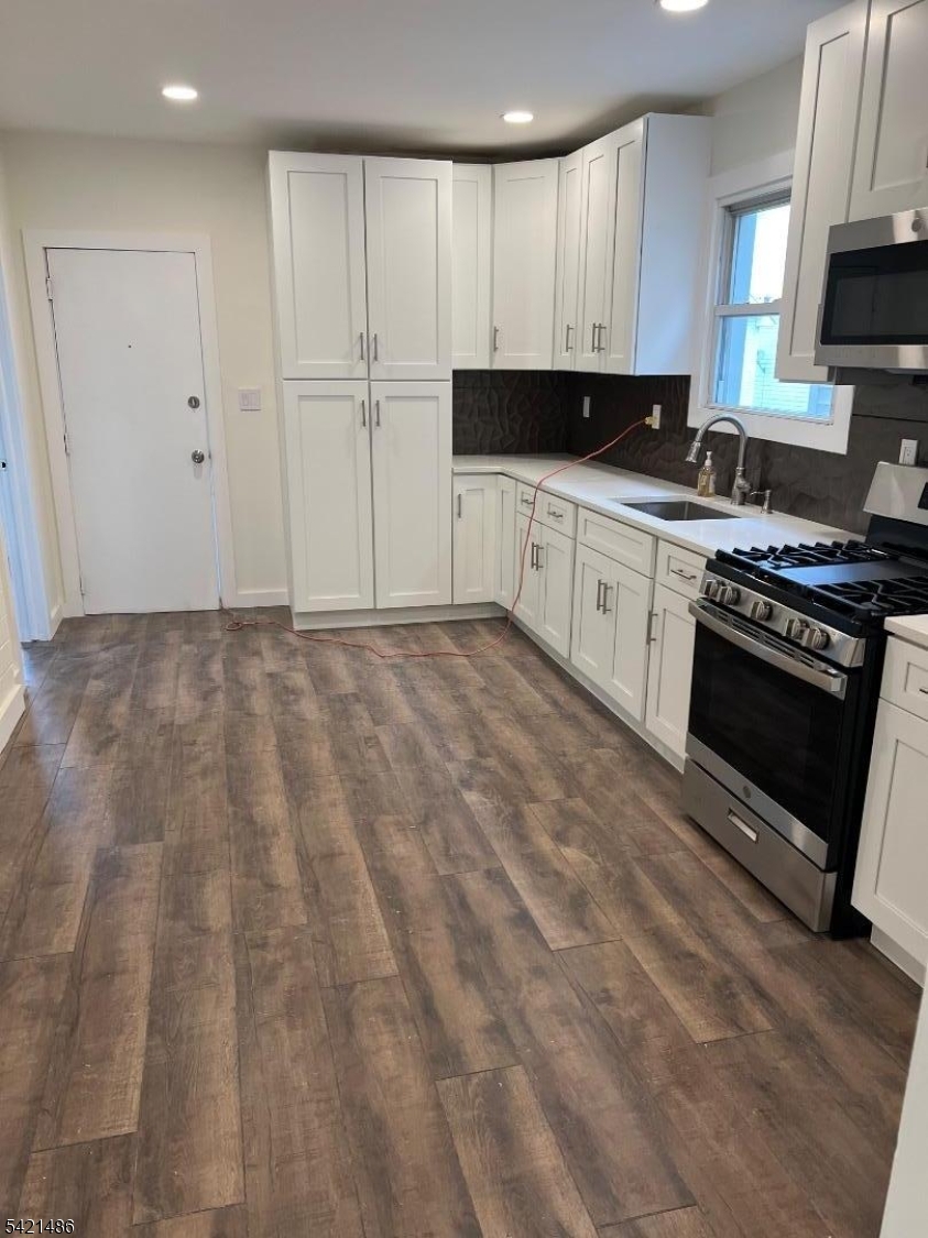 227 Palmer Street, Unit 1 Elizabeth, NJ 07202 - Photo 3 of 7 a kitchen with granite countertop a stove a sink and a microwave