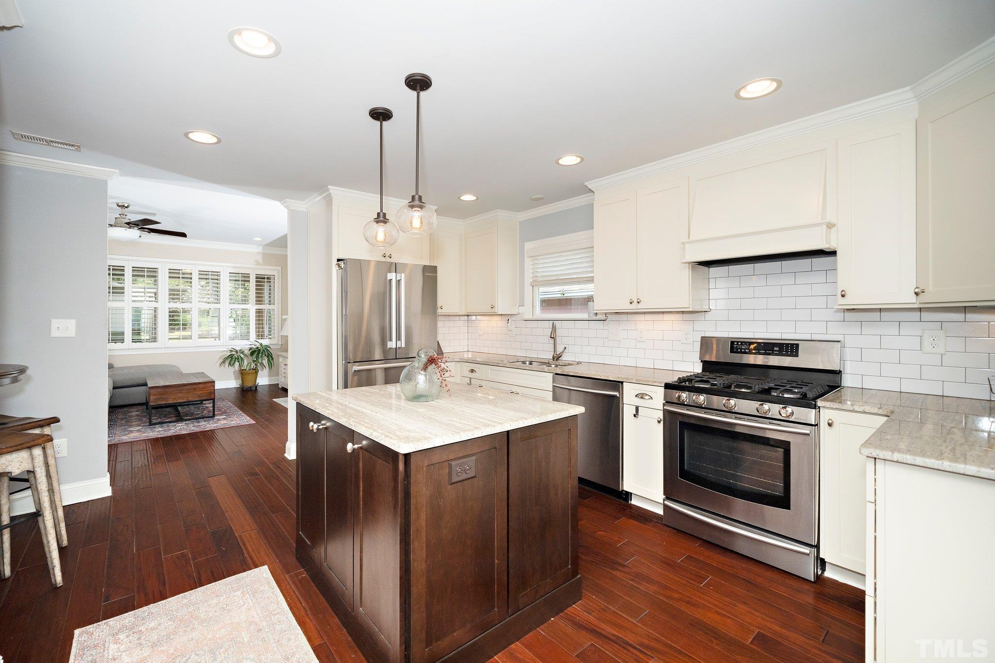 606 North Boundary Street Raleigh, NC 27604 - Photo 3 of 16 a kitchen with a stove a sink dishwasher a refrigerator and a dining table with wooden floor