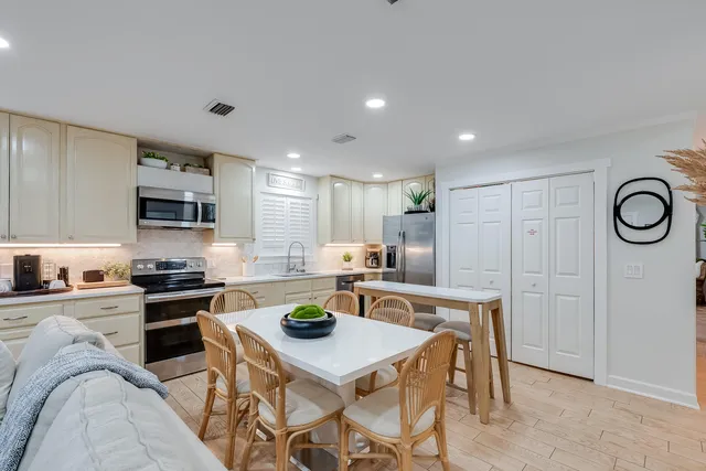 a kitchen with a stove a sink dishwasher a refrigerator with white cabinets and wooden floor