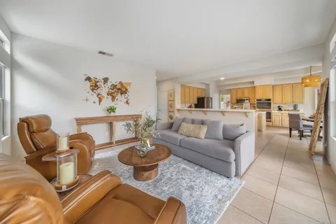a living room with furniture kitchen view and a large window