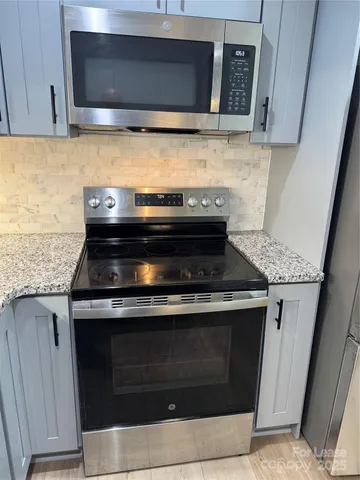 a view of a refrigerator in kitchen and an empty room with wooden floor