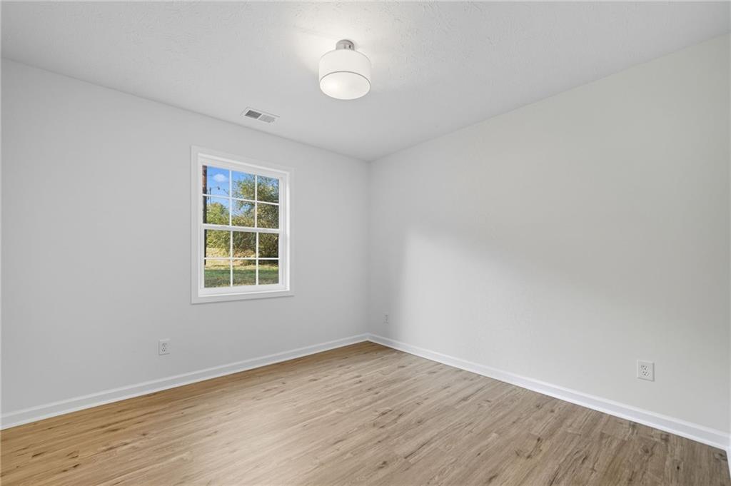 6964 Wheeler Road Lula, GA 30554 - Photo 16 of 27 an empty room with wooden floor and a window