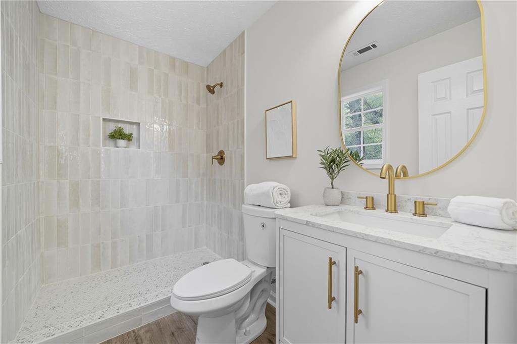 6964 Wheeler Road Lula, GA 30554 - Photo 19 of 27 a bathroom with a granite countertop sink a toilet and a mirror