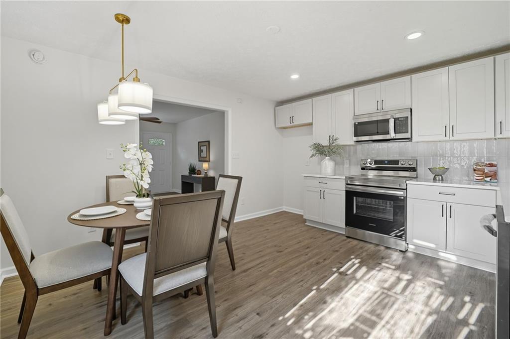 6964 Wheeler Road Lula, GA 30554 - Photo 10 of 27 a kitchen with granite countertop a dining table chairs and a refrigerator