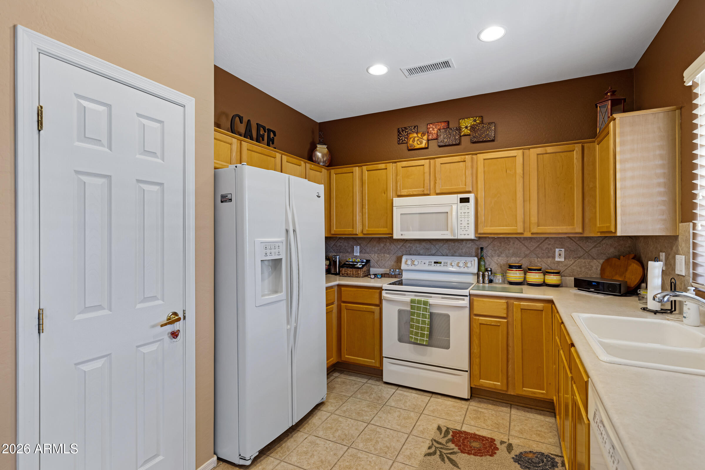 19253 North Hunters Run Surprise, AZ 85387 - Photo 12 of 30 a kitchen with a refrigerator a sink and cabinets