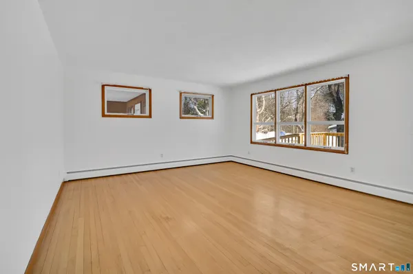 a view of an empty room with a window and wooden floor