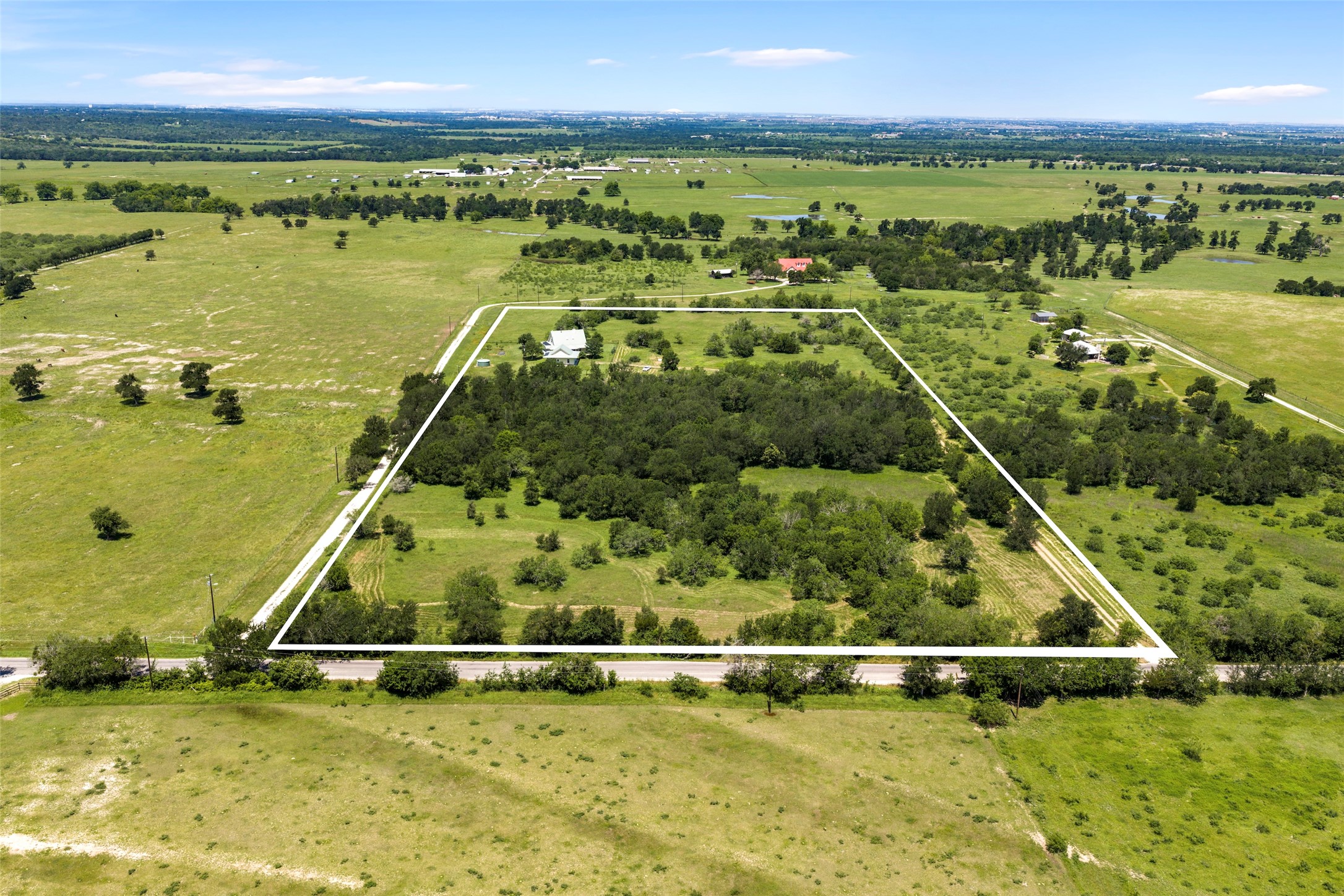 Expansive rural property featuring a mix of open grassy areas and mature tree coverage.