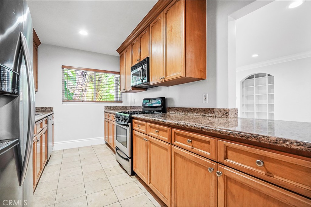 14934 Dickens Street, Unit 15 Sherman Oaks, CA 91403 - Photo 6 of 15 a kitchen with stainless steel appliances granite countertop a stove a sink and a microwave
