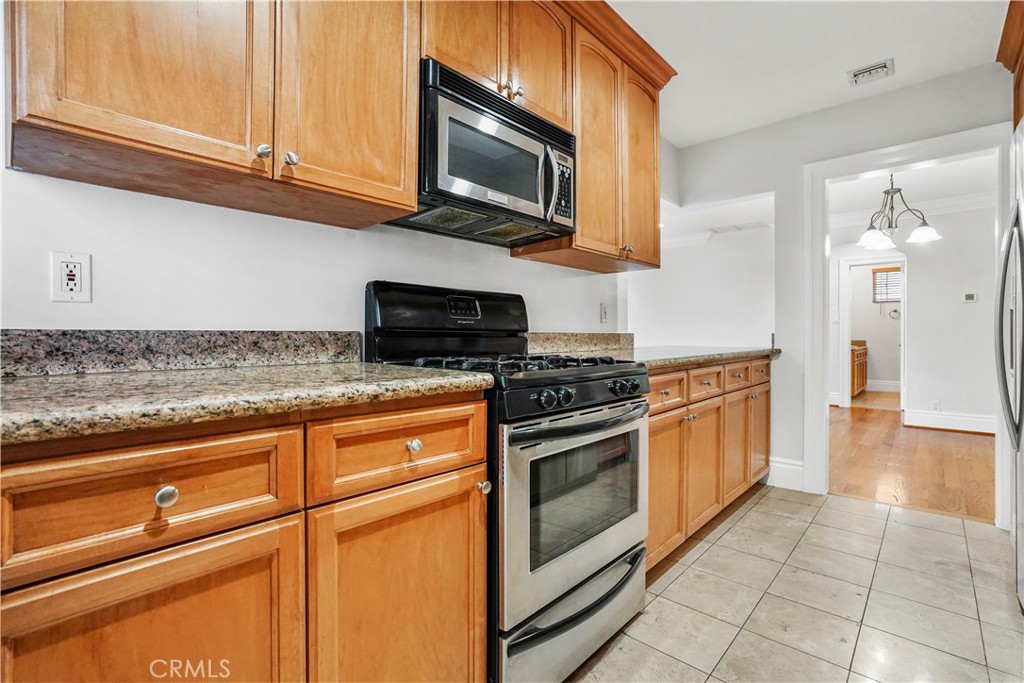 14934 Dickens Street, Unit 15 Sherman Oaks, CA 91403 - Photo 7 of 15 a kitchen with stainless steel appliances granite countertop a stove microwave and cabinets